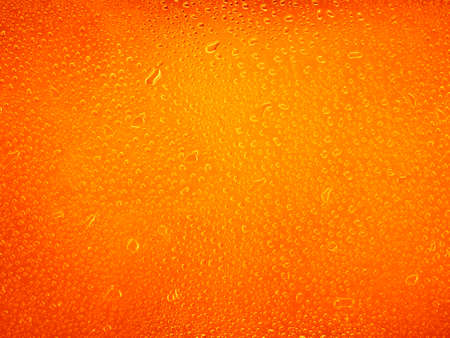 Water drops on orange background texture. backdrop glass covered with drops of water
