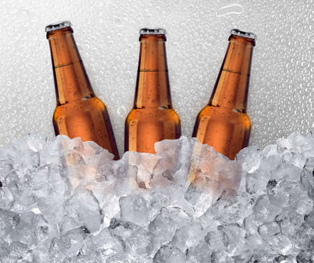 Three beer bottles getting cool in ice cubes. water drop backgroundの写真素材
