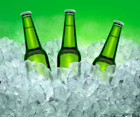 Three beer bottles getting cool in ice cubes. on the White color smoke backgroundの写真素材