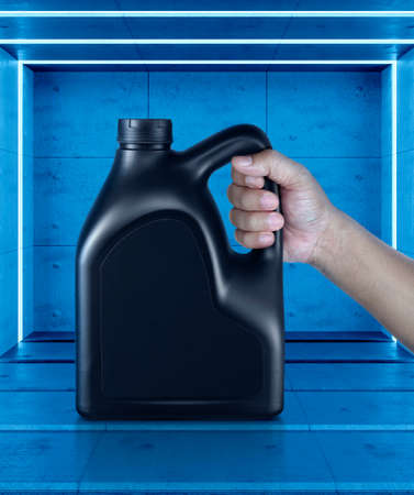A canister with engine oil in a hand. on Abstract blue room interior with White neon lampsの写真素材