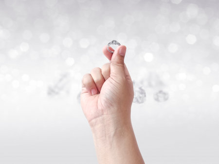 Hand holding diamond ring on shining bokeh backgroundの写真素材