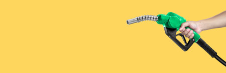 Hands holding Fuel nozzle on yellow backgroundの写真素材