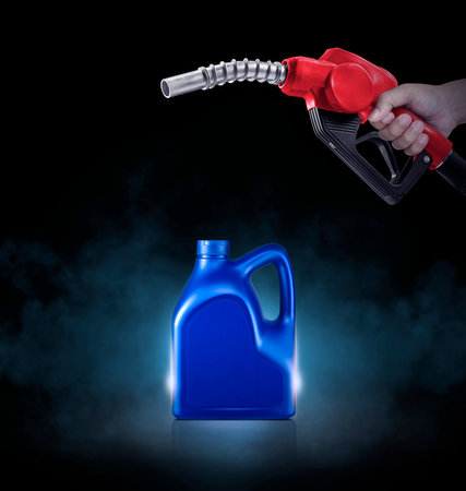 Hands holding Fuel nozzle and blue bottle of engine oil on black background with smokeの写真素材
