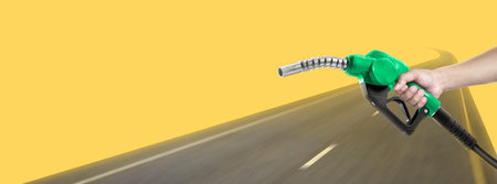Hands holding a fuel nozzle and the blur the streetの写真素材