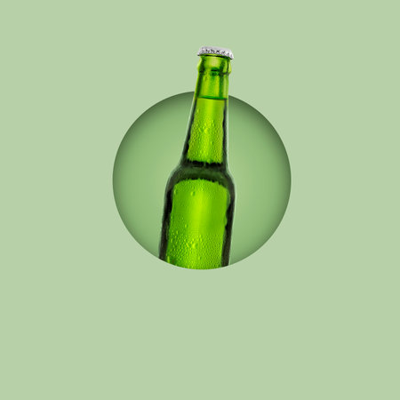 Green bottle of fresh beer with drops of condensation on pastel green backgroundの写真素材