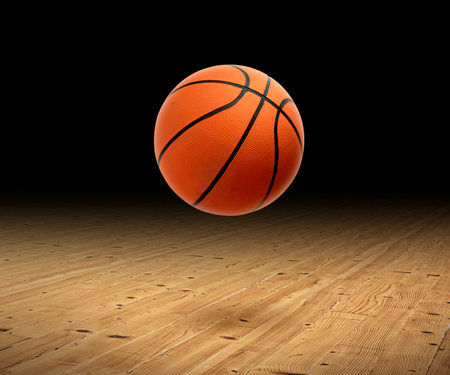 A basketball with a dark background on a hardwood gym floorの写真素材