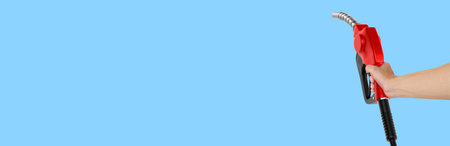 Hands holding Fuel nozzle on light blue  backgroundの写真素材