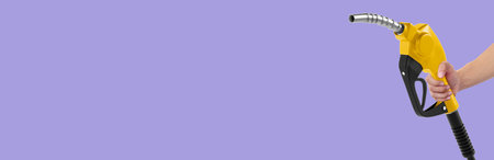 Hands holding Fuel nozzle on light purple backgroundの写真素材