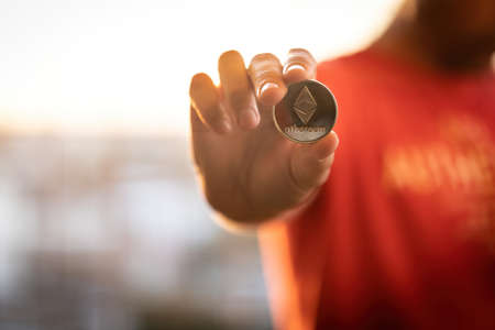 Men Handhold ethereum silver Coin with the acronym ETH. Ethereum is one of the main cryptocurrencies and assest on blockchain exchanges which investors choose to protect their savings.の写真素材