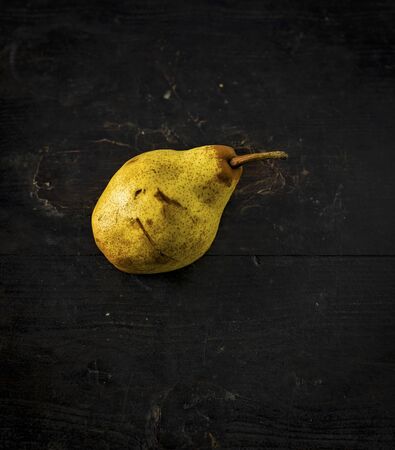 Pear over a dark wooden table, shabby rustic mood.の写真素材
