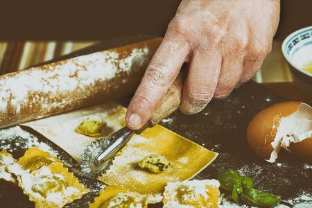 Preparing ravioli in the kitchen with tools and ingredients : dough, flour, eggs, stuffing, cutter, roller, board.の写真素材