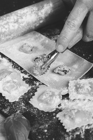 Preparing ravioli in the kitchen with tools and ingredients : dough, flour, eggs, stuffing, cutter, roller, board.の写真素材