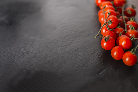 Cherry tomatoes over a black stone plate with copy space.の写真素材