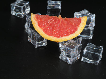 A slice of fresh rose grapefruit on black stone background flat layの写真素材