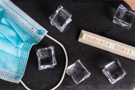 coronavirus icons as facial mask and folding meter on black background representing social...