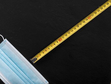 coronavirus icons as facial mask and folding meter on black background representing social distancing concept educational clear wayの写真素材