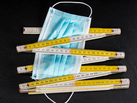 coronavirus icons as facial mask and folding meter on black background representing social distancing concept educational clear wayの写真素材