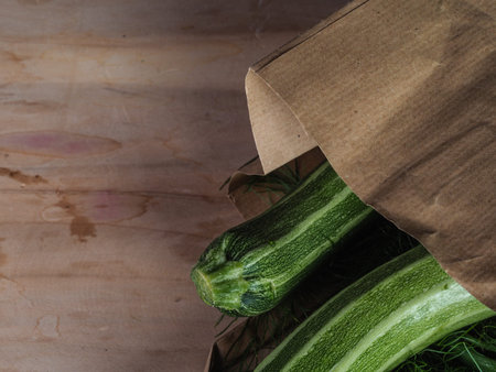 Overhead shot of a group of isolated three green biologic zucchini veggies fruit over a light brown...