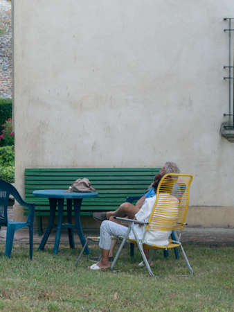 Cheerful aged husband and wife relaxing on lawnの写真素材