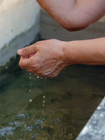 Woman watering and washing on a public foutain in CastellArquato Italy.Pure and precious to nature....