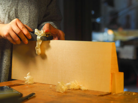 Close up of professional master artisan luthier painstaking detailed work on wood violin in a...