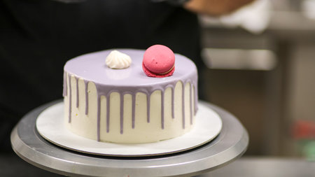 chef usign macaron, flowers and text sign for a celebration cake