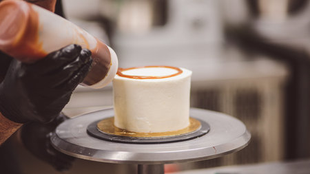 chef decorating the top of a frosted buttercream cake