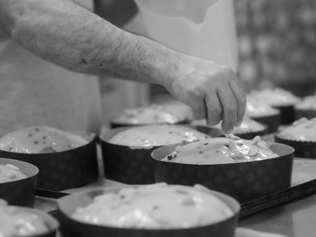 chef topping panettone italian cake with almonds