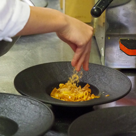 closeup of a chef hand wearing gloves serving and decorating a plate of pasta