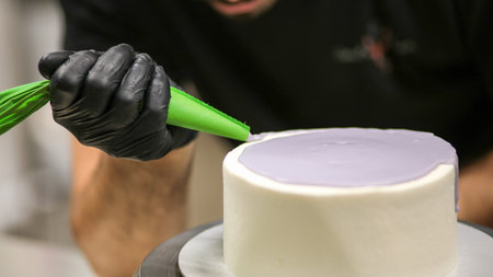 chef using using bag decorating a frosted icing cake