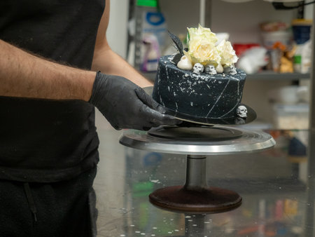 pastry chef baker topping birthday black airbrush painted frosted cake, two real roses silver sprayed and edible chocolate skull toppers, silver brush strokesの写真素材