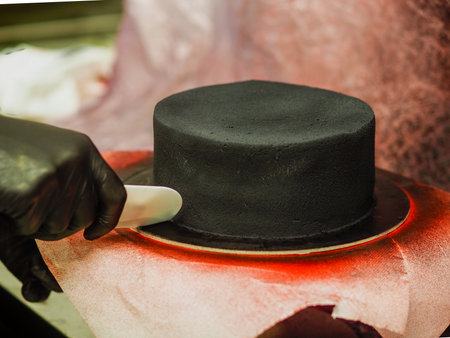 chef preparing frosted black painted cup cake with blue turquoise dripping and colored handmade meringue toppingの写真素材