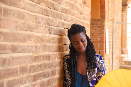 Portrait of an African woman with dreadlocks braid with umbrella parasol. Happy young woman feeling...