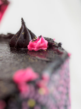 frosted icing black decorate cake for birthday celebration, real rose topping and pink sweet swirls studio isolated shotの写真素材