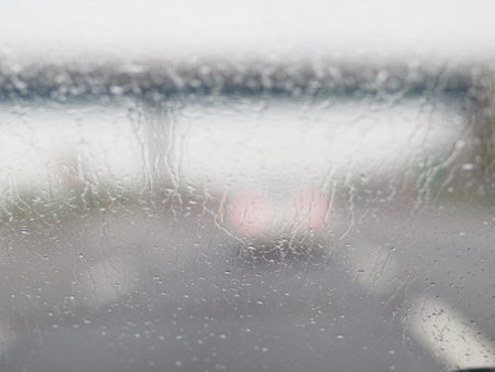 A blurry image of a busy street with cars and a truck. The rain is making the windshield of the cars...
