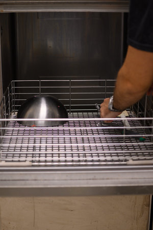 staff cleaning professional cook appliances and ware in professional kitchen, secure hygiene concept