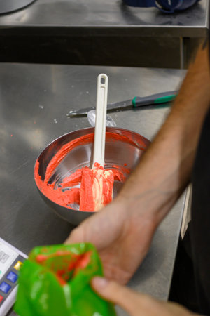 pastry chef styr red butter cream for cake decoration in professional kitchenの写真素材