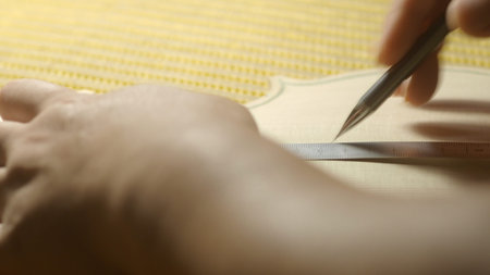 Luthier meticulously working on the cello top in the workshop, carefully drawing lines with a ruler...