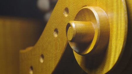 Close up of luthier's meticulous work crafting fine tuning pegs onto the neck of a cello, showcasing...