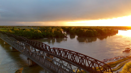 Iron Bridge, road and railway viaduct crossing Po River in Cremona, Lombardy, Italy, connecting two banks at sunset with metal arches and brick pylonsの写真素材