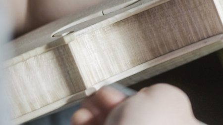 Close-up of the hands of a violin maker working on a violin
