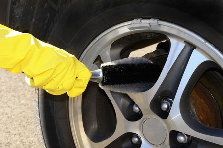 Woman's hand with a rim brush cleaning a wheel of an SUV carの写真素材