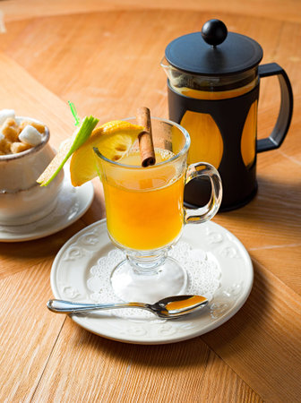 Glass teapot and cup with orange fruit tea on wooden tableの写真素材