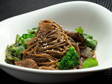 Buckwheat noodles with chicken and vegetables in Japanese style, on white plateの写真素材