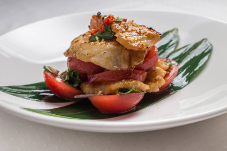 codfish with tomatoes on white plateの写真素材