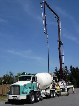 Concrete truck mixer discharging concrete into a truck-mounted pump connected to a flexible hose that moves the material to the construction site.の写真素材