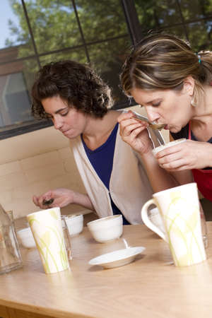 two women taste and compare brewed coffees at a cafe  Process is known as Coffee Cupping の写真素材