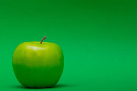 a left justified plastic green apple on a green background の写真素材