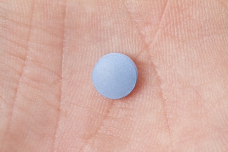 A macro shot of a small medical pill in the palm of a hand  shot from above  pill is blank for inscriptions or text の写真素材