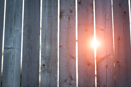 the sun peeks through breaks in the old fence の写真素材